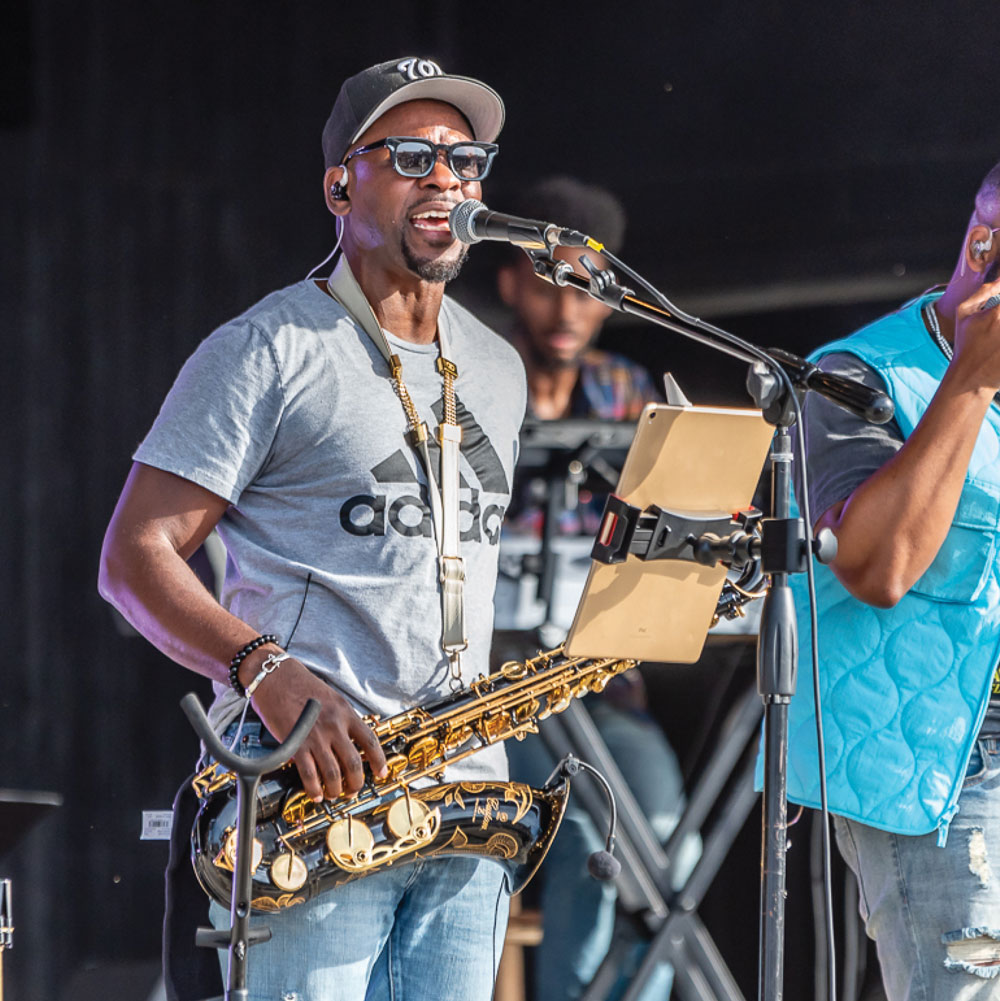 Musician playing saxophone on stage with an iPad on a stand.