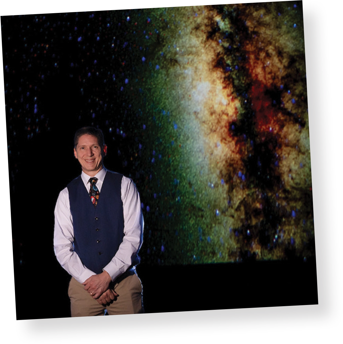Chris Fragile posing for a photo in front of a space background