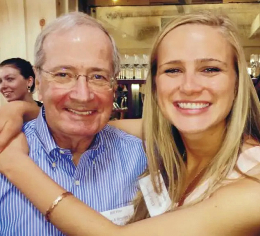 An older man and a young woman smiling closely together indoors.