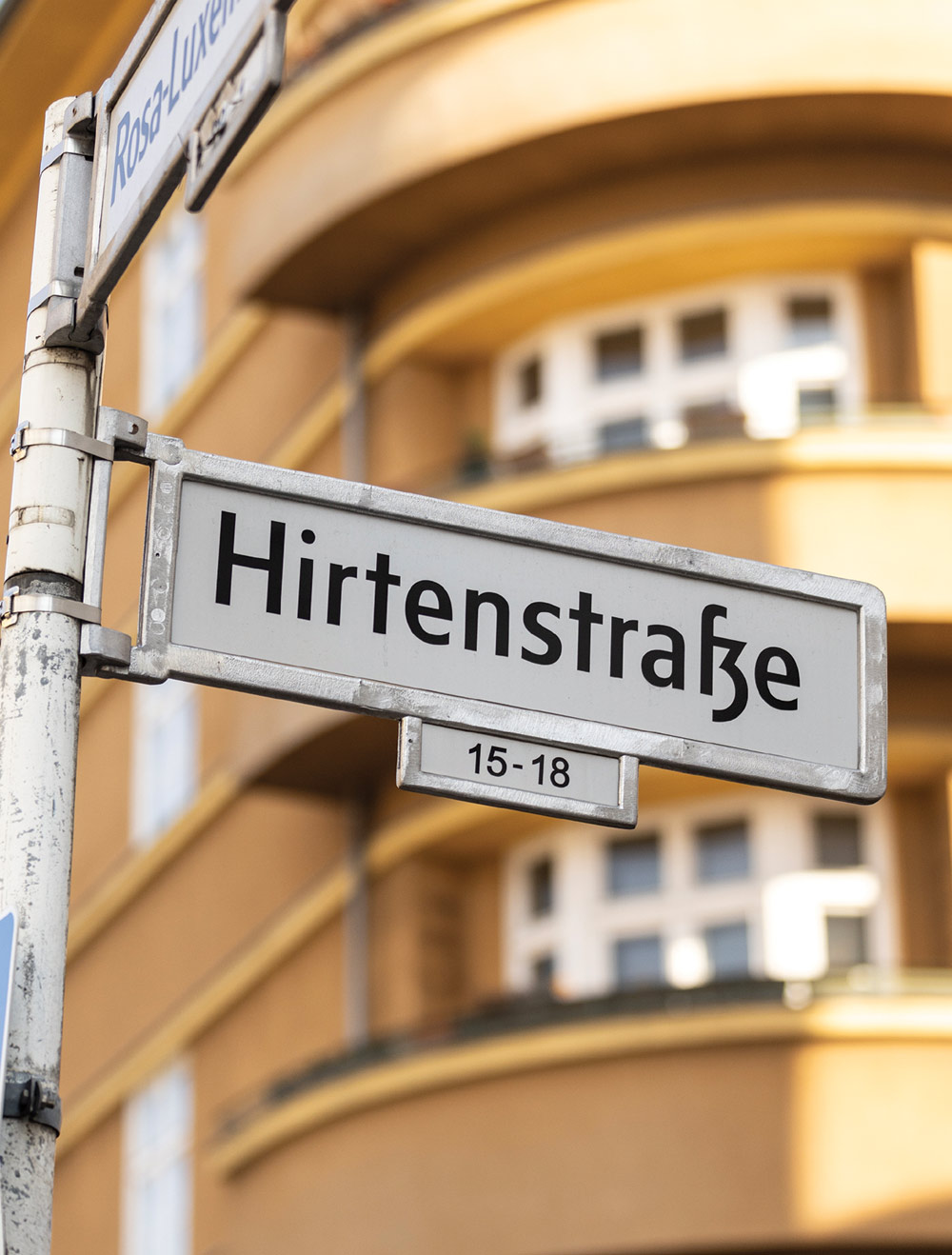 Street signs for Rosa-Luxemburg-Straße and Hirtenstraße with a building in the background.