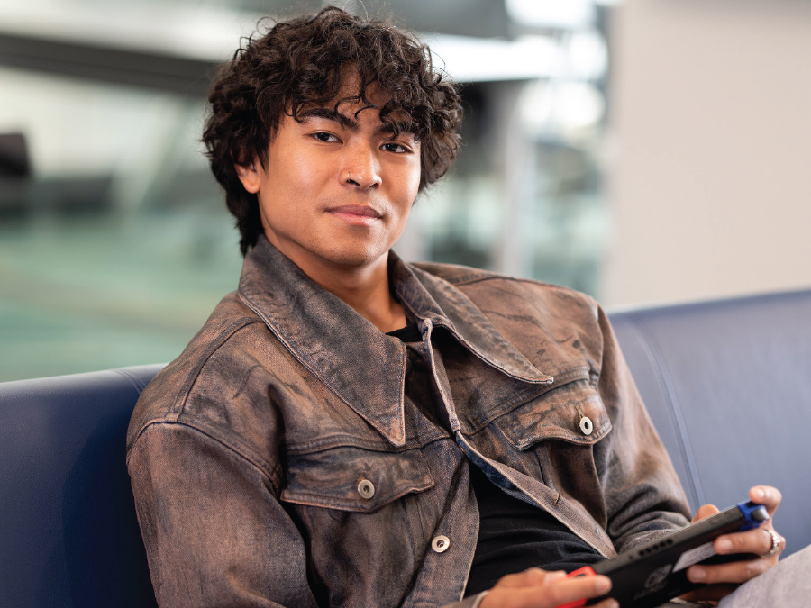 Kyle Barretto sitting in chair with brown denim jacket