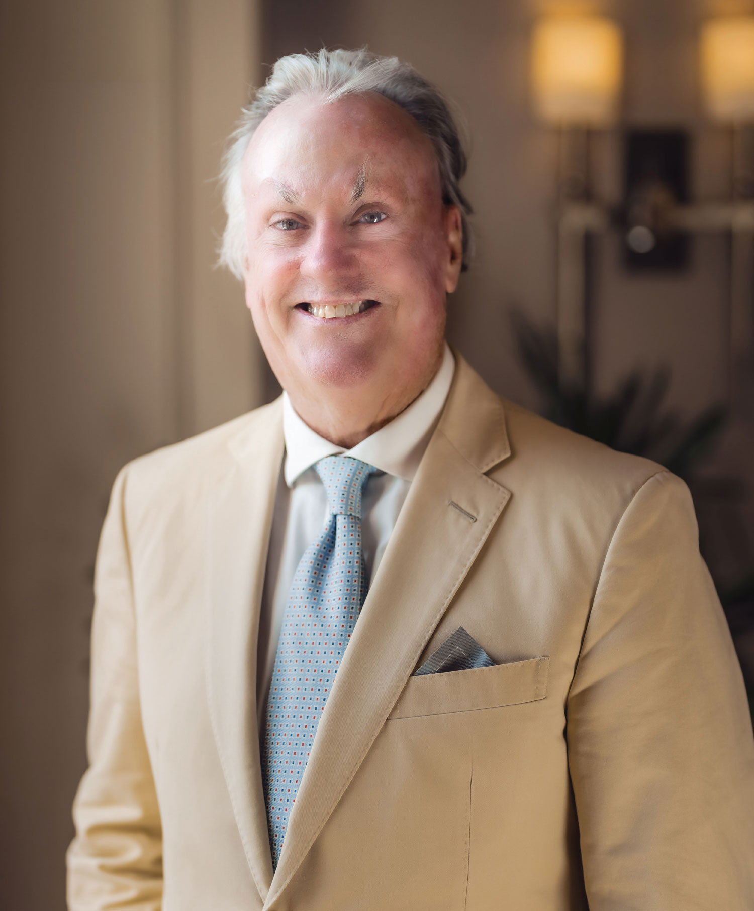 Michael Bennett smiling in tan suit with blue and orange dotted tie