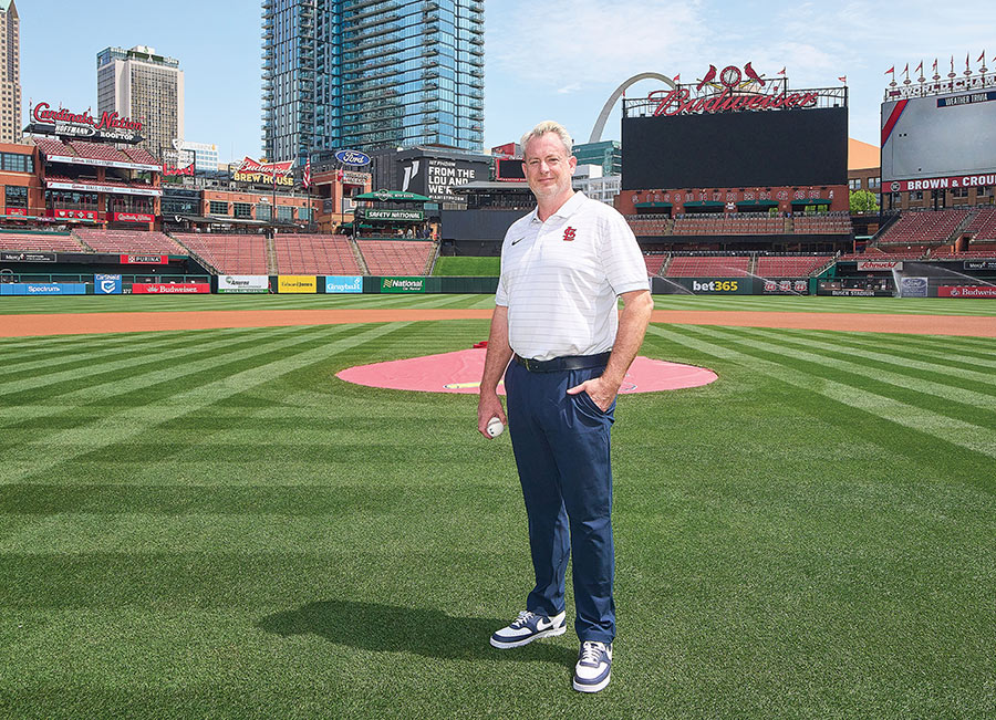 Chris Conroy stands on a baseball field at Busch Stadium holding a baseball.