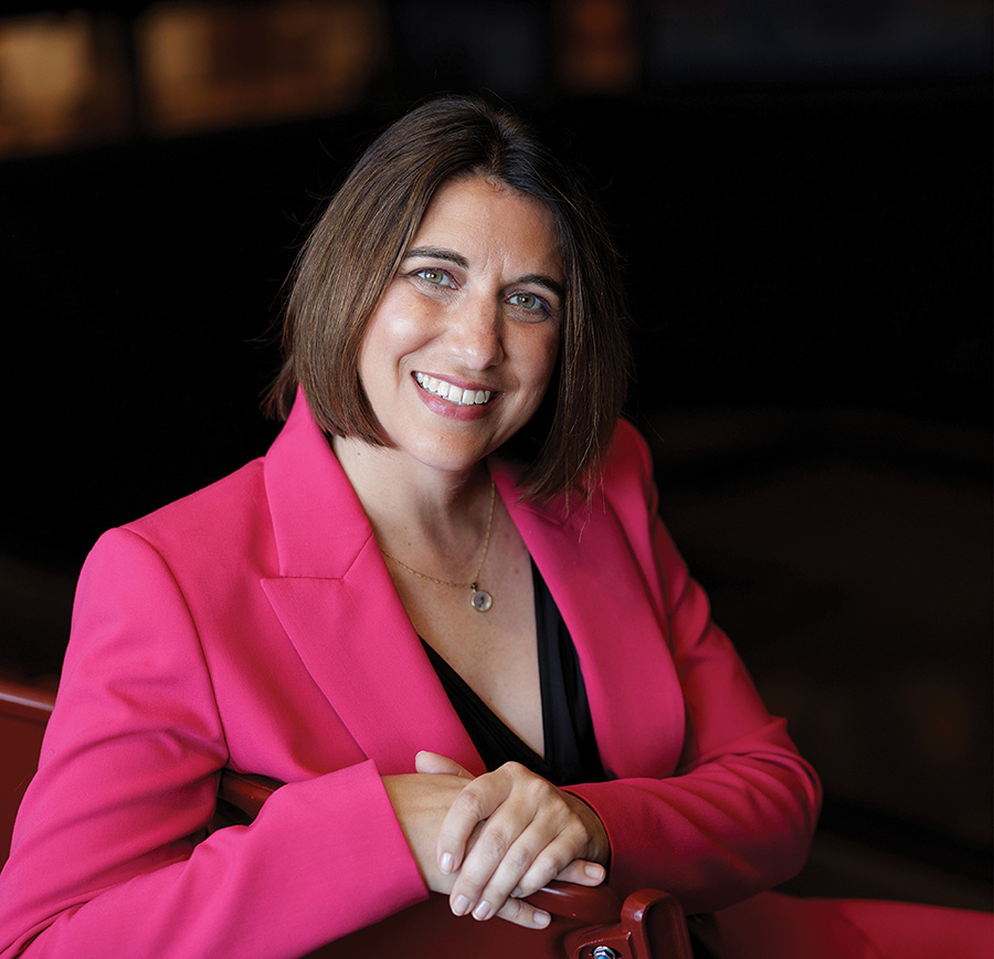 Kate Tiller wears a bright pink blazer over a black top.